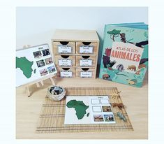 a wooden table topped with lots of books and pictures next to boxes filled with animals