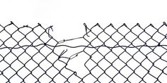 a black and white photo of a chain link fence with barbed wire on the top