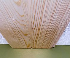 the corner of a wood paneled ceiling with white paint and green trim on it