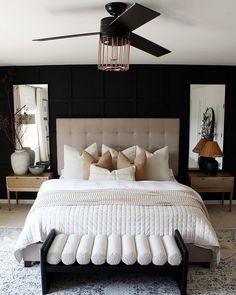 a bedroom with black walls and white bedding has a chandelier hanging from the ceiling