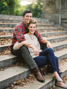 a man and woman sitting on steps in the fall with their arms around each other