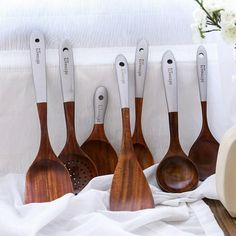 six wooden spoons lined up next to each other on top of a white cloth