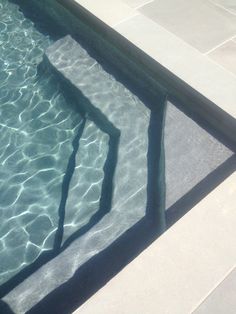 an empty swimming pool with clear water and sun reflecting on the floor, as seen from above