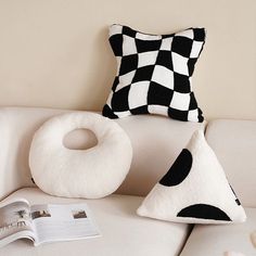 a white couch with two pillows and a pillow on it next to a small book