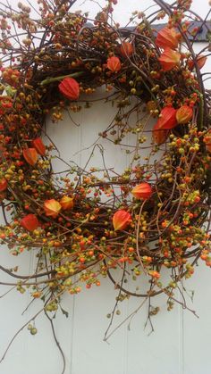 a wreath with orange and yellow flowers hanging on the side of a white door,