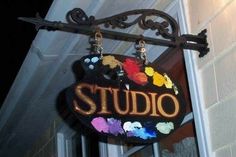 a sign hanging from the side of a building that says studio with flowers painted on it