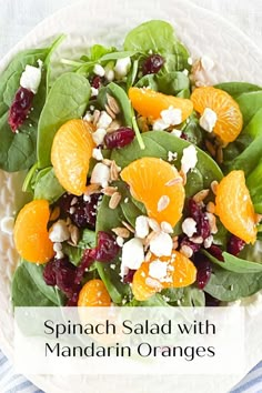 spinach salad with mandarin oranges and feta cheese in a white bowl on a striped cloth