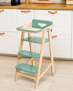 a wooden baby high chair sitting on top of a hard wood floor in a kitchen