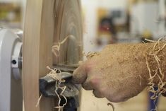 a person working on a machine with their hands in the wheel and wood shavings