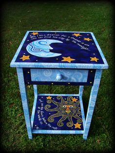 a night stand with an octopus and stars painted on the side, sitting in grass