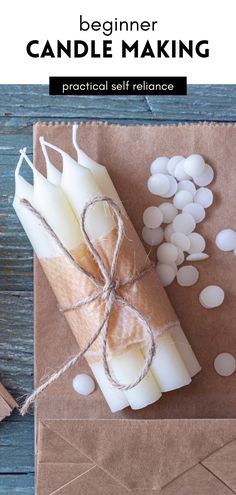 a candle is wrapped in brown paper and surrounded by small white pebbles on a wooden table