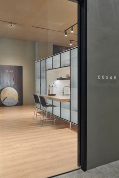 an empty room with chairs and artwork on the wall behind glass doors that say cesar