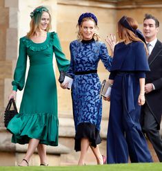 two women in green dresses and one woman in blue dress are talking to each other