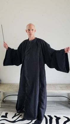 a man dressed in black holding a wand