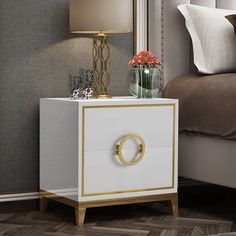 a white and gold bedside table with flowers on it next to a bed in a bedroom