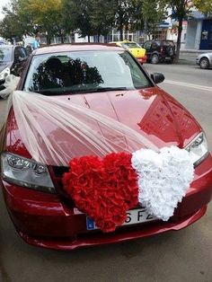 a red car with a heart shaped decoration on the hood