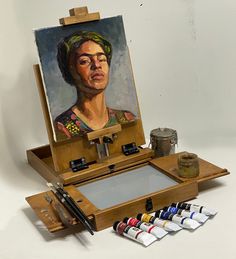 an artist's easel with paint and watercolors on it