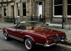 an old red convertible car parked on the street