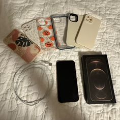 four cell phones are laying on a bed next to an empty container and other items