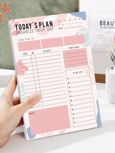 a person holding up a planner on top of a table