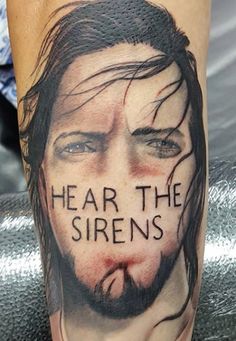 a man's leg with the words hear the sirens on it and his face