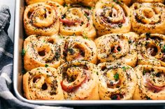 a pan filled with ham rolls covered in cheese and sprinkled with parsley