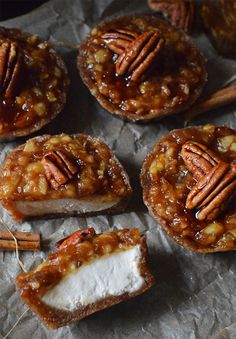 several pecan pies are sitting on wax paper with cinnamon sticks sticking out of them