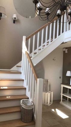 a white staircase leading up to the second floor with chandelier and lamps on either side