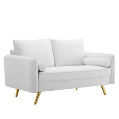 a white couch with gold legs and pillows