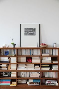 a bookshelf filled with lots of books in front of a wall mounted poster