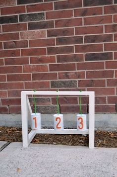 three white cups with numbers on them sitting in front of a brick wall and some grass