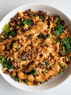 a white bowl filled with meat and veggies covered in gravy on top of a table