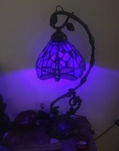 a lamp that is on top of a table with purple lights in the room behind it