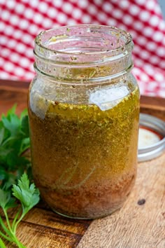 a jar filled with green seasoning sitting on top of a wooden cutting board next to parsley