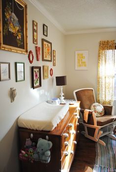 a baby's crib in the corner of a room with pictures on the wall