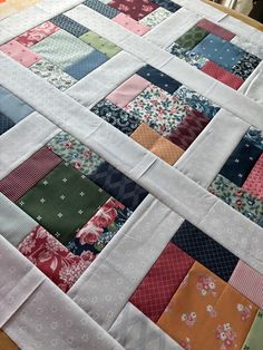 a quilted table topper with many different colored squares on it