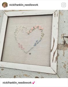 an embroidered heart in a white frame with pink and blue flowers