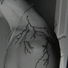 the back of a man's shoulder with lightning tattoos on his left arm and chest