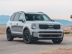 the front end of a white suv parked in a desert