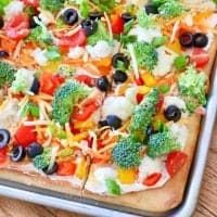 a pizza sitting on top of a pan covered in veggies