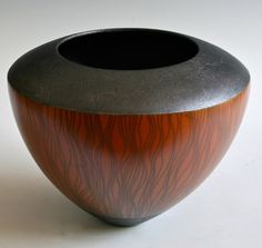 a black and brown vase sitting on top of a white table