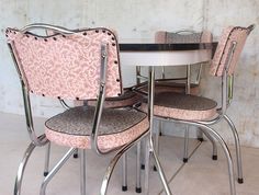 a dining table with four chairs and a small round table in front of the wall