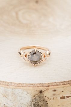 a diamond ring sitting on top of a piece of wood in front of a wooden table