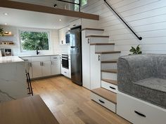 an open concept kitchen and living room with stairs leading up to the loft