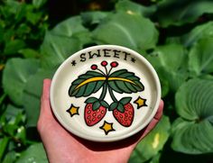 a hand holding a small white plate with strawberries on it and the words sweet written in black