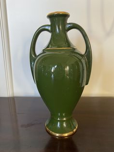 a green vase sitting on top of a wooden table