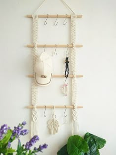 there is a wall hanging with hooks on it and some plants in the corner next to it