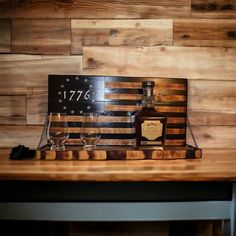 an american flag and two wine glasses on top of a wooden table next to a sign