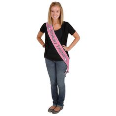 a woman standing with her hands on her hips wearing a pink sash and smiling at the camera