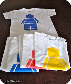 four t - shirts with legos on them sitting on a wooden table next to each other